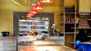 A bar area with a long counter, shelves with bottles, and a variety of glassware. - Podere La Torre (Schio)