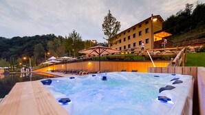 A hot tub area with a wooden deck, lounge chairs, and a building in the background. - Podere La Torre (Schio)
