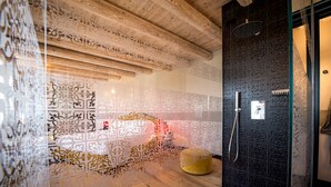 A modern bathroom with a wooden ceiling, decorative wall panels, a yellow ottoman, and a shower area. - Podere La Torre (Schio)