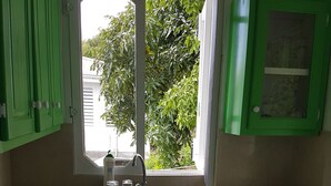 Eine kompakte Küche mit grünen Schränken, einer eingebauten Waschmaschine, einem Spülbecken mit Fenster darüber und einem Herd.