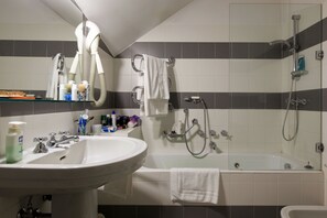 Un baño con lavamanos, espejo, secador de pelo y bañera con ducha.