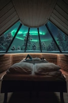 Una habitación con cama, ventana y vistas de las auroras boreales.