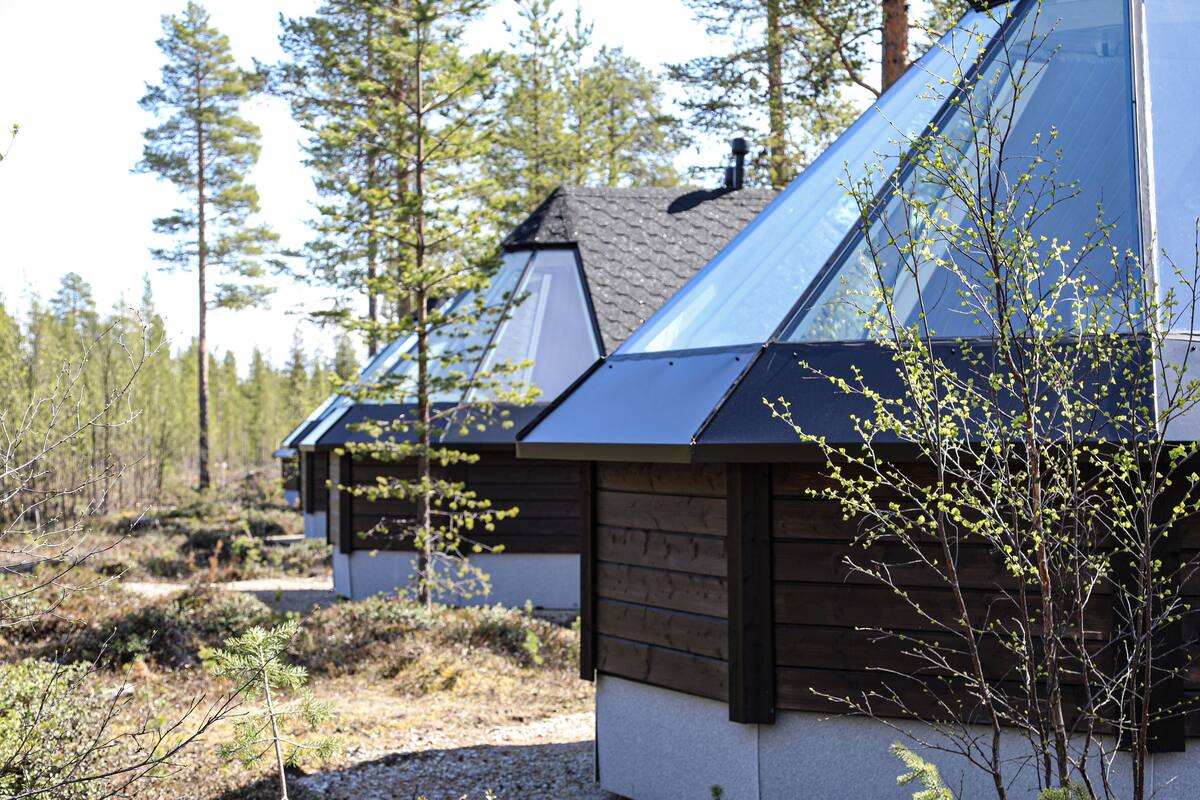 A row of cabins with sloped roofs, surrounded by a forested area.