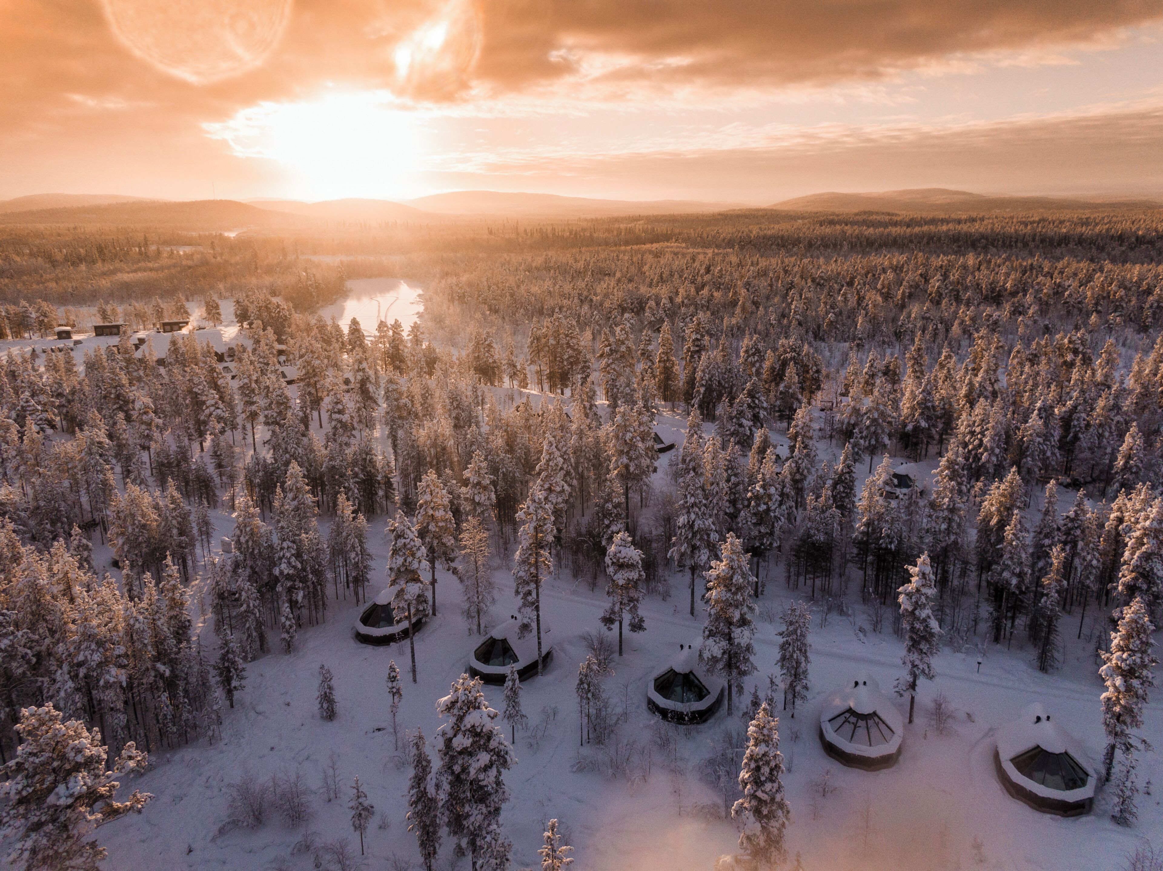 Sneklædt skov med flere yurts.