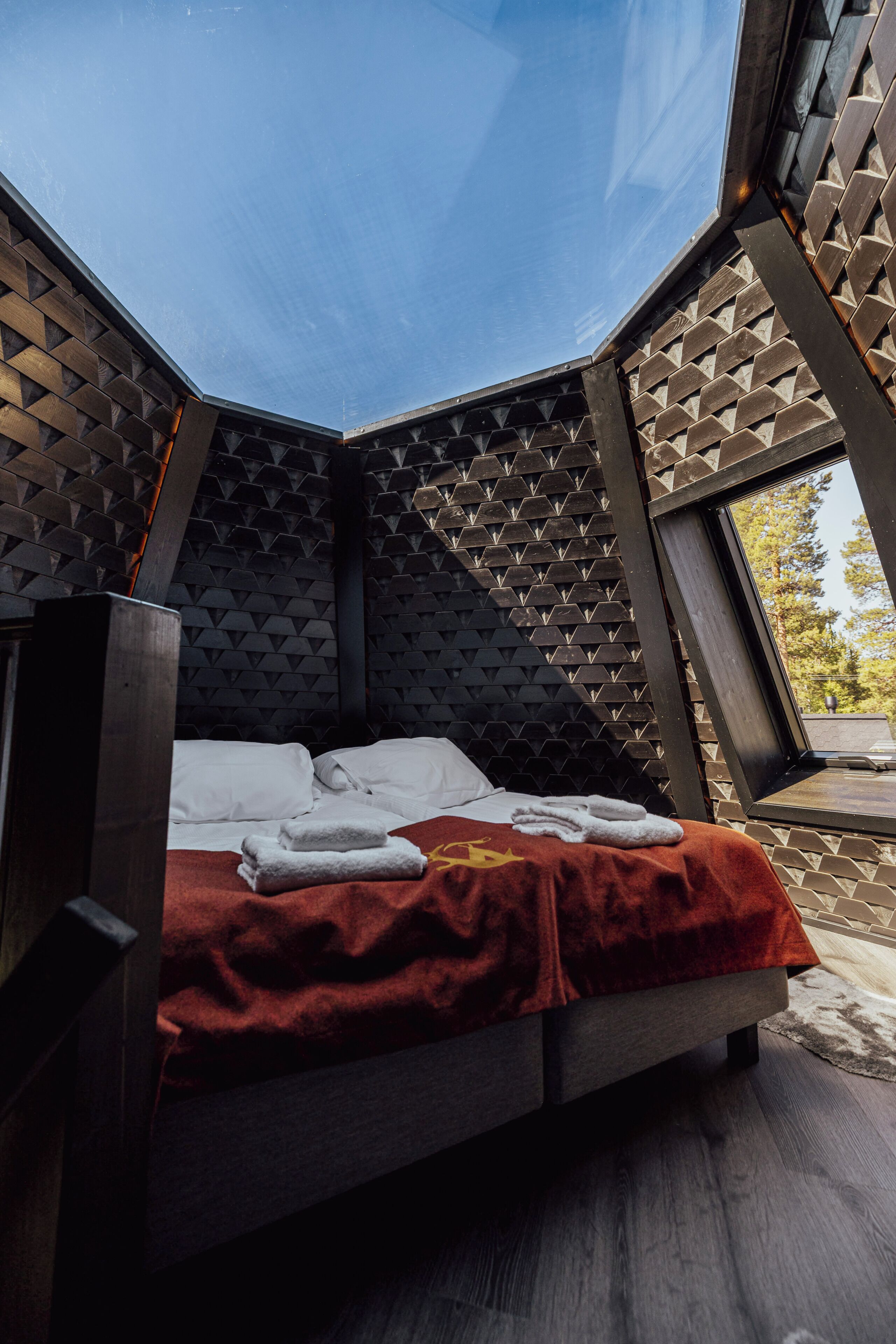 Una cama en una habitación con pared de diseño geométrico y una ventana.
