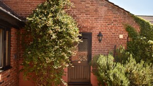 A brick building with a wooden door and steps leading up to it. - At the Farmhouse Hunters Hall (Dereham)