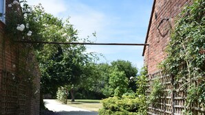 A brick pathway leading to a building with a wooden fence and a metal antenna. - At the Farmhouse Hunters Hall (Dereham)