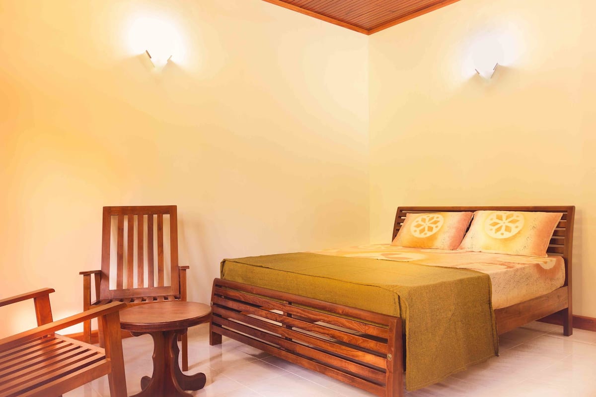 A bedroom with a wooden bed, a wooden chair, and a small table.