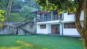 A modern two-story building with a flat roof, large windows, and a stone staircase leading to the upper level. - AA Circuit bungalow (Kandy)