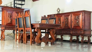 A traditional wooden dining set with intricate carvings, a staircase, and a chandelier. - AA Circuit bungalow (Kandy)