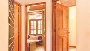 A hallway with a wooden door, a window with blinds, and a bed with a mattress and pillows. - AA Circuit bungalow (Kandy)
