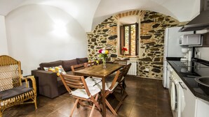 Un comedor acogedor con pared de piedra, una mesa de madera y un sofá.