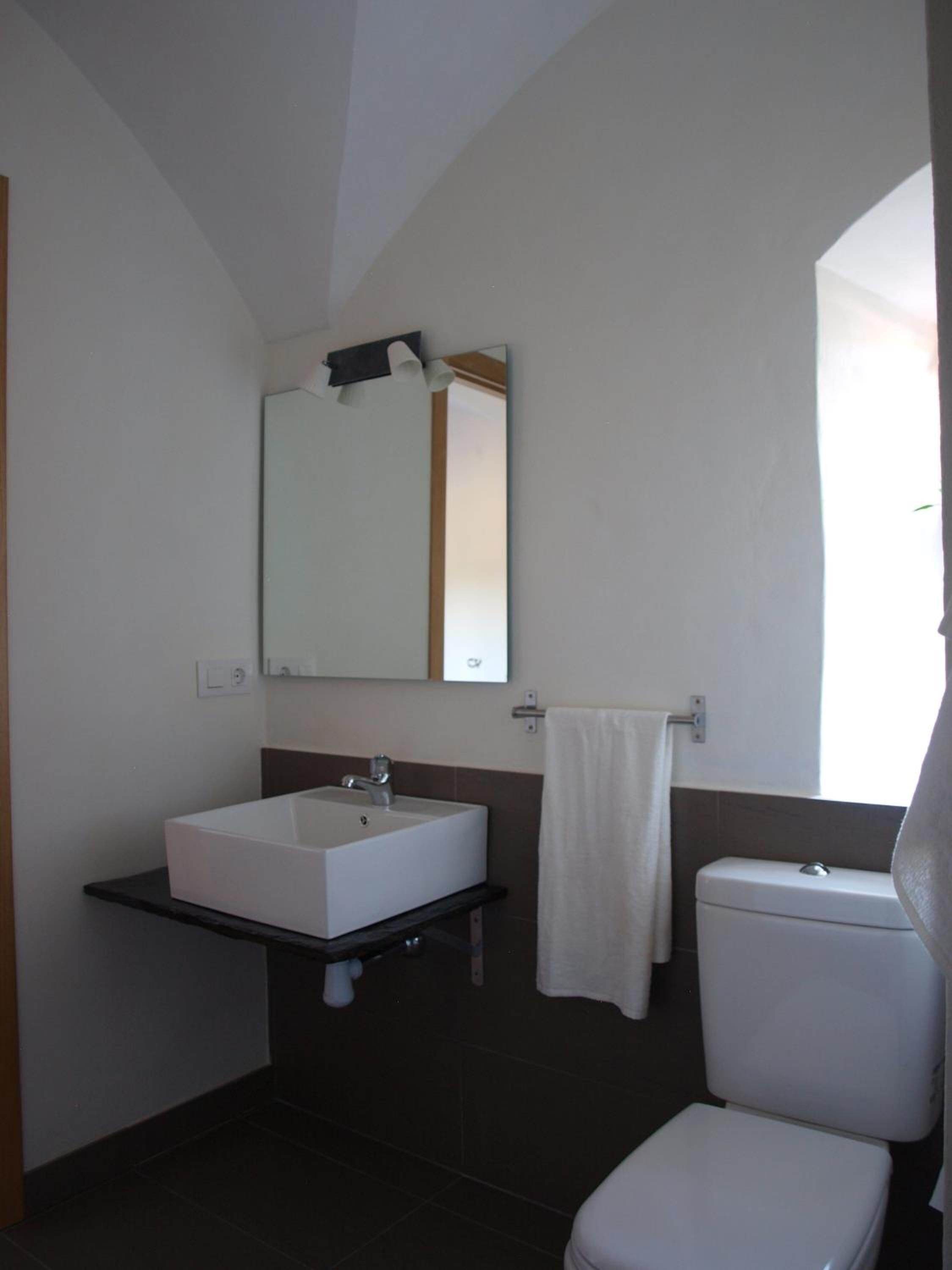 Een badkamer met een wit wastafelmeubel, spiegel en toilet.