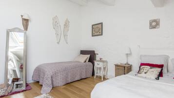 Een slaapkamer met een bed, nachtkastje, dressoir, spiegel en decoratieve objecten aan de muur.