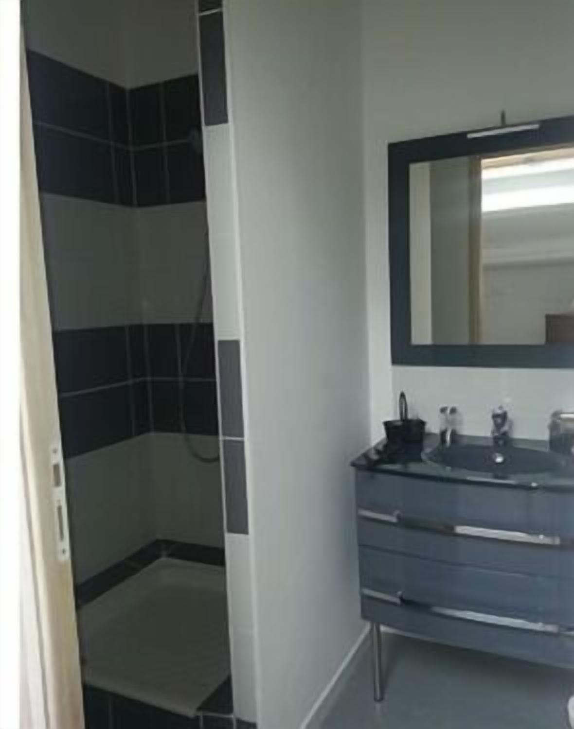 Une salle de bain équipée d’une douche, d’un miroir et d’un meuble-lavabo avec un évier et des articles de toilette.