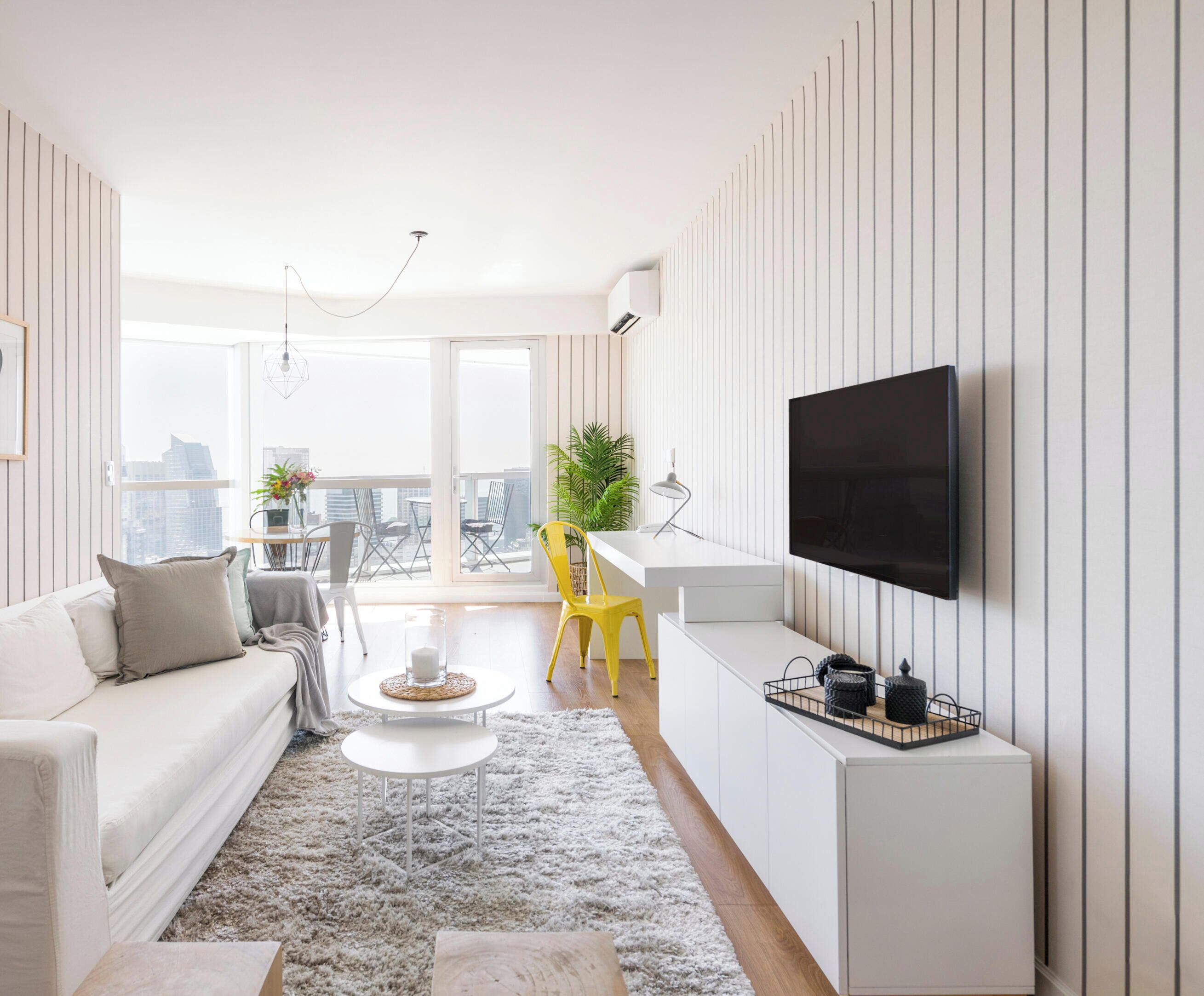 Una sala de estar moderna con sofá, mesa de centro y televisor montado en la pared.