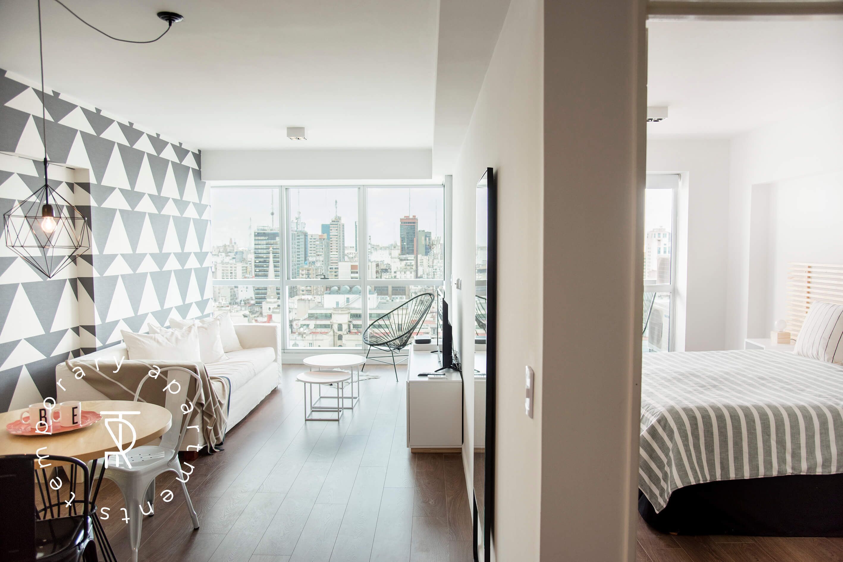Una habitación de hotel moderna con vistas a la ciudad, un sofá, un comedor y una cama.