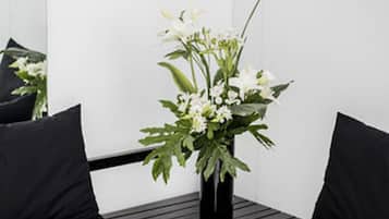 Et hjørnesæde med sorte polstrede stole og en sort vase med hvide blomster.