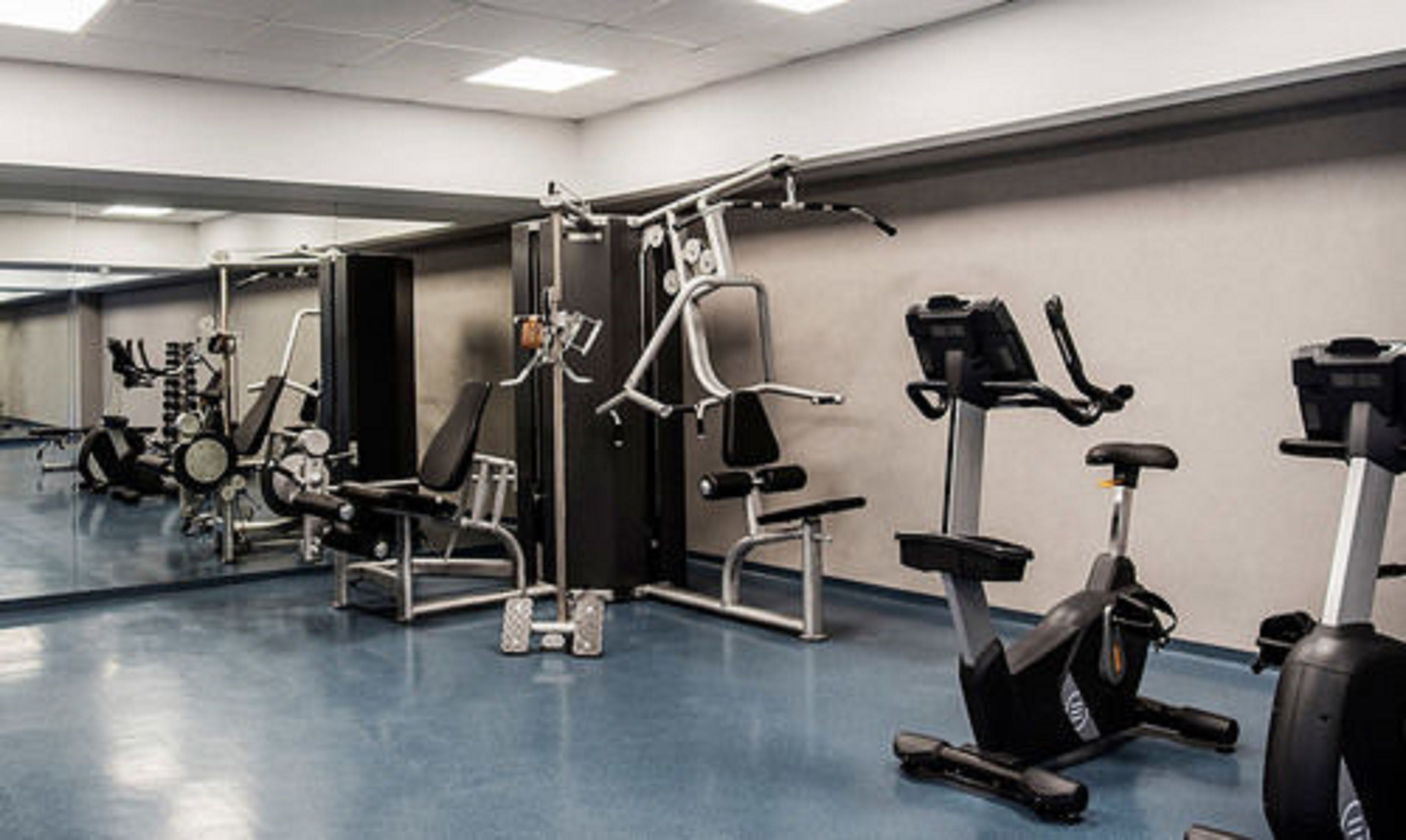 Une salle de sport équipée de divers appareils d’exercice, notamment des tapis de course, des vélos d’appartement et des appareils de musculation.