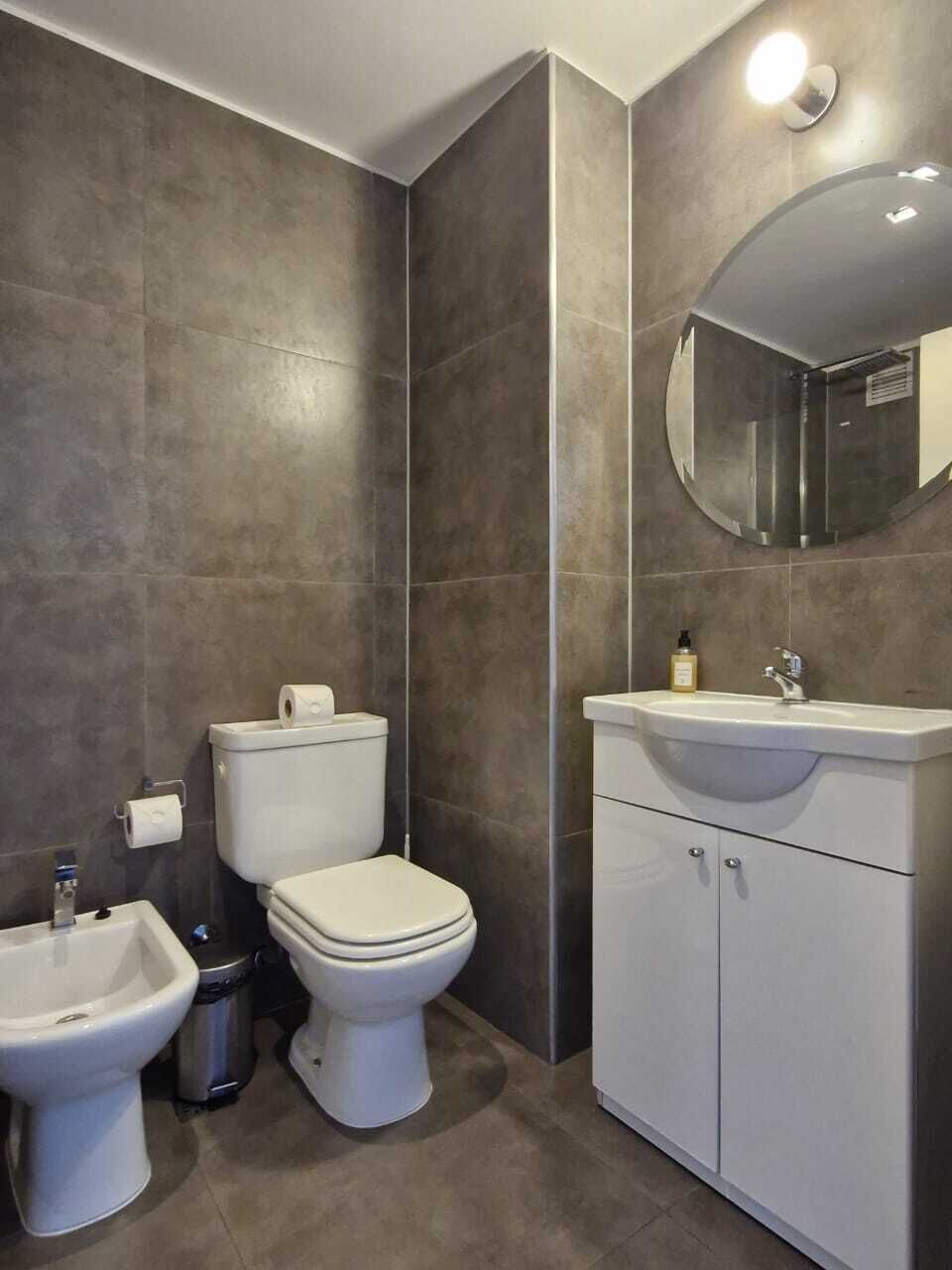 Baño con inodoro, bidé, lavabo y espejo.