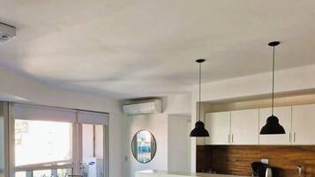 Una sala de estar moderna con sofá, mesa de comedor, sillas e iluminación colgante.