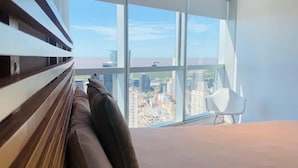 A modern bedroom with a large window, a bed, and a chair. - Top Rentals Downtown (Buenos Aires)