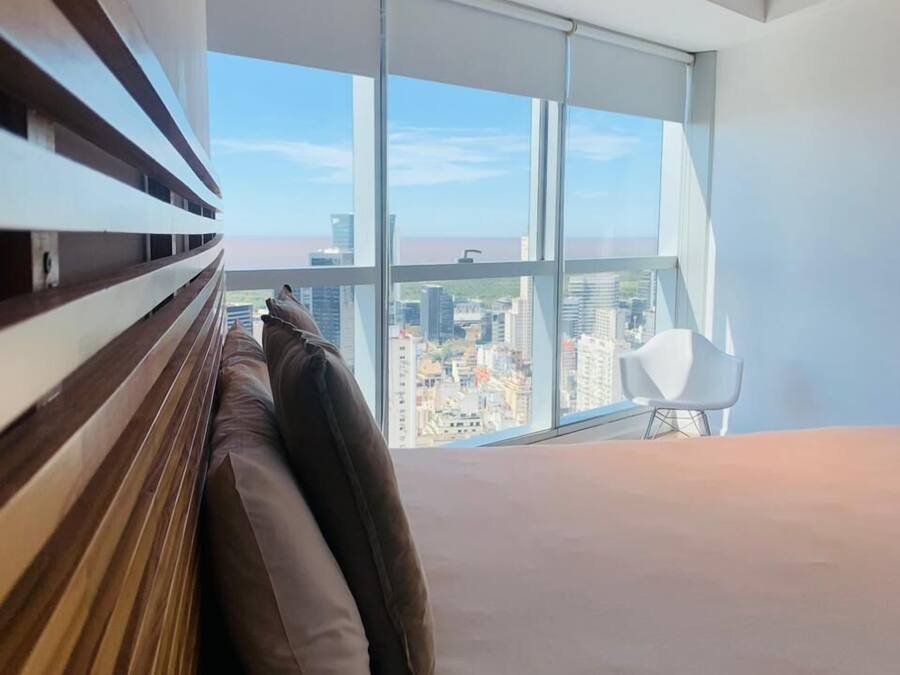 Een moderne slaapkamer met een groot raam, een bed en een stoel.