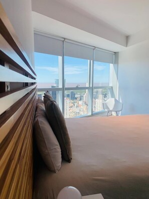 A modern bedroom with a large window, a bed, and a chair. - Top Rentals Downtown (Buenos Aires)