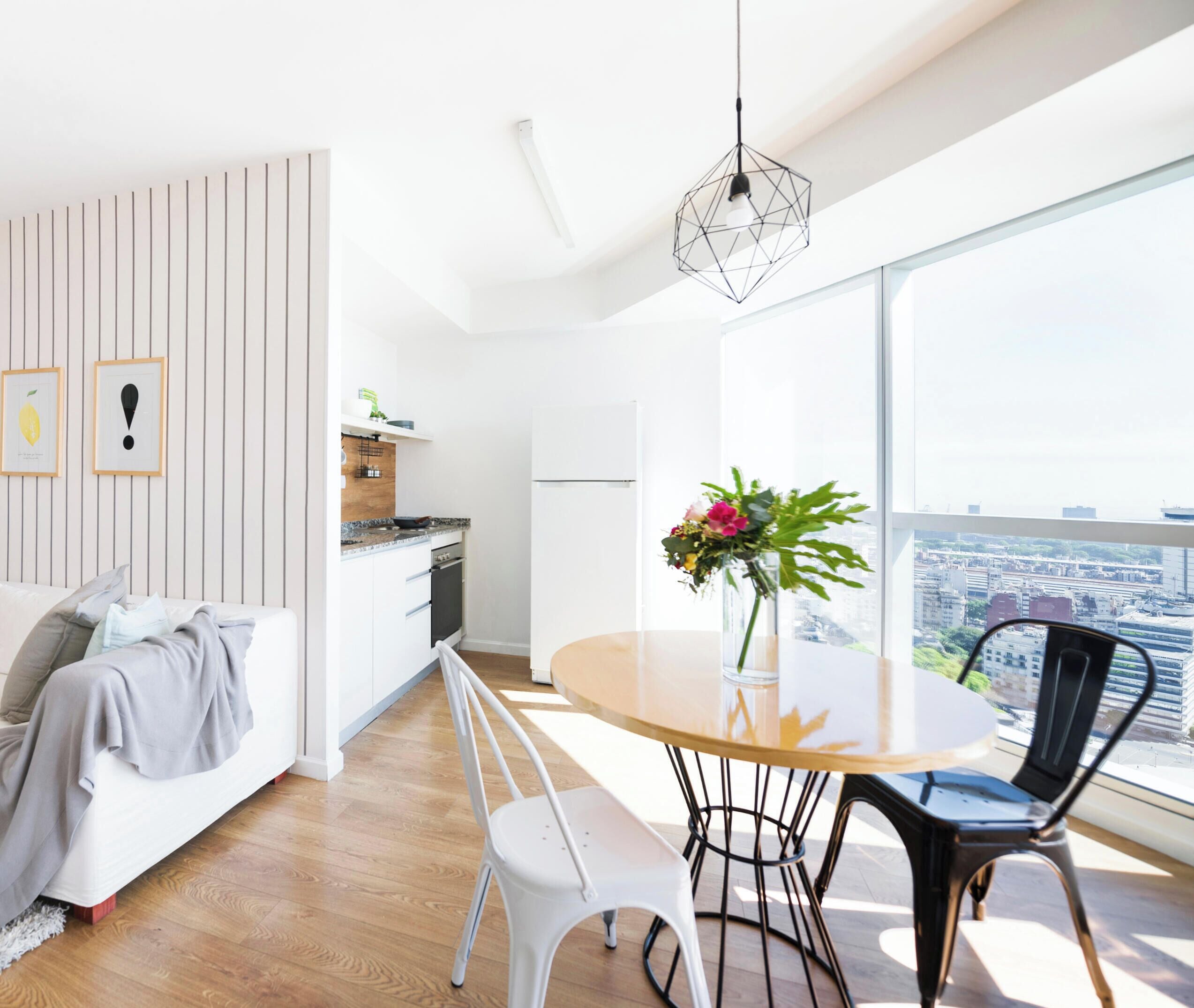 Un espacio habitable moderno con comedor, cocina y ventanas amplias con vista a la ciudad.