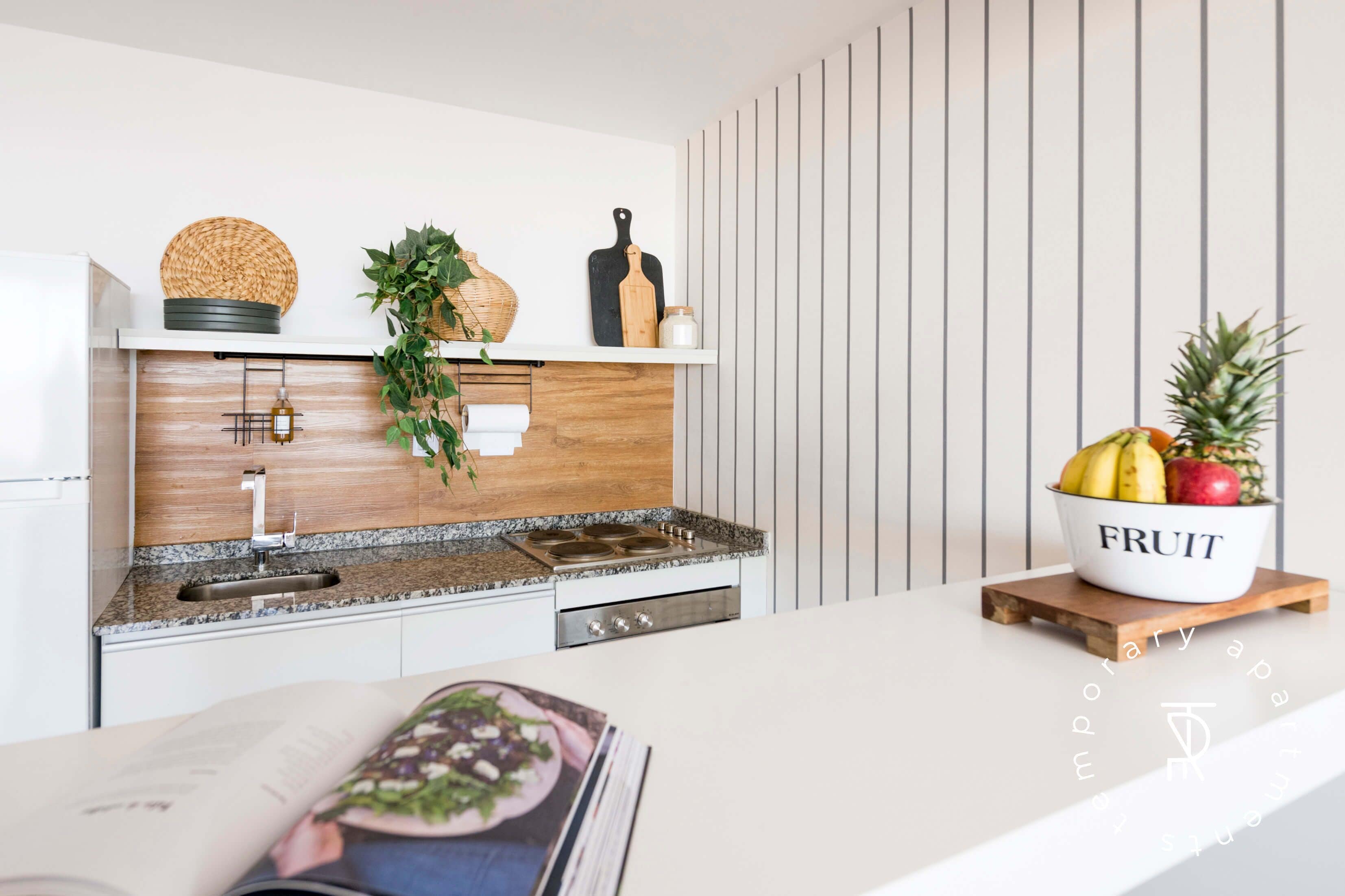 A modern kitchen with a white countertop, wooden backsplash, and a built-in stove.