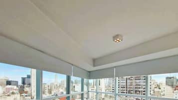 Una habitación de hotel moderna con un ventanal grande, una cama y vistas a la ciudad.