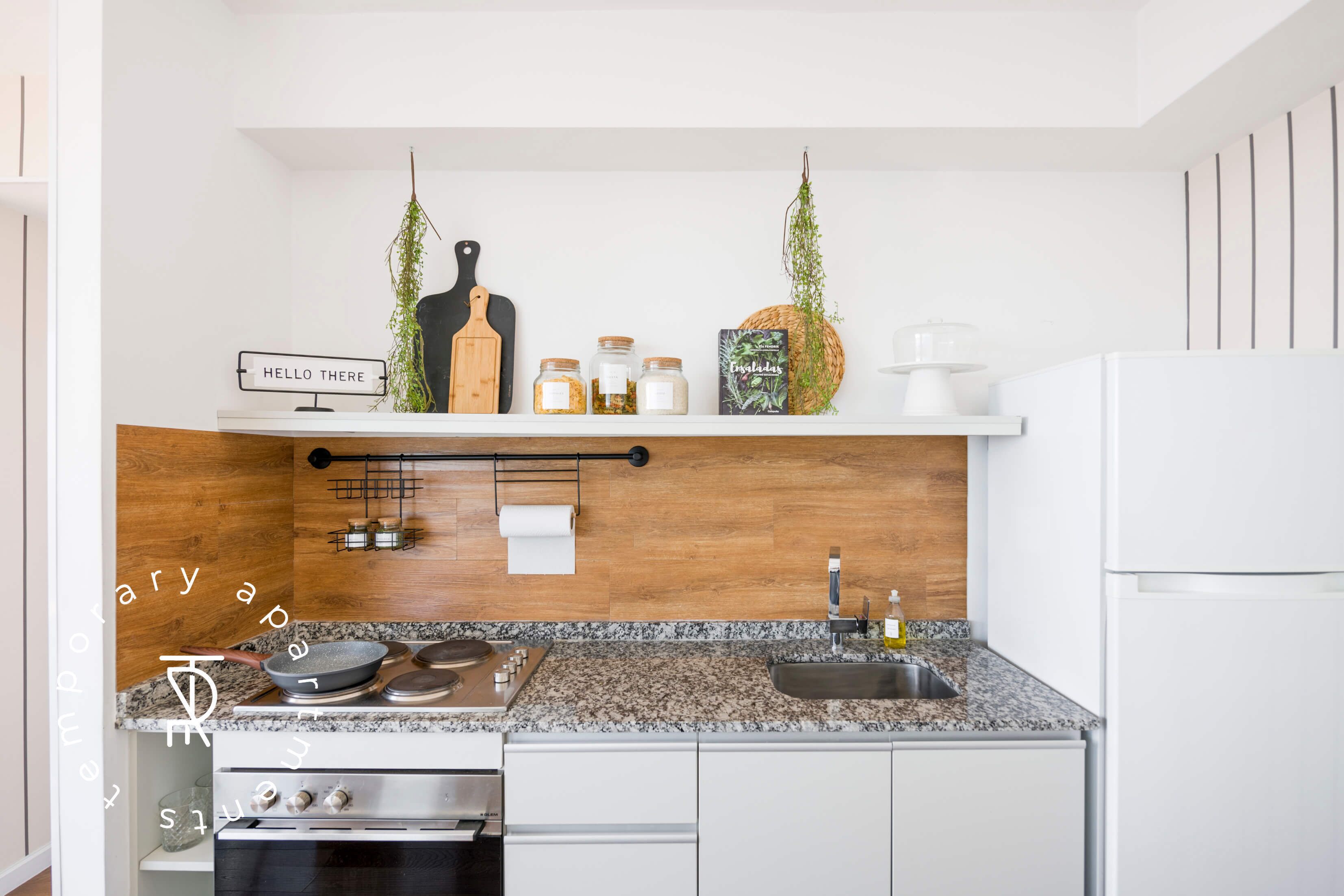 A modern kitchen with a wooden backsplash, a gas stove, a sink, and a white refrigerator.