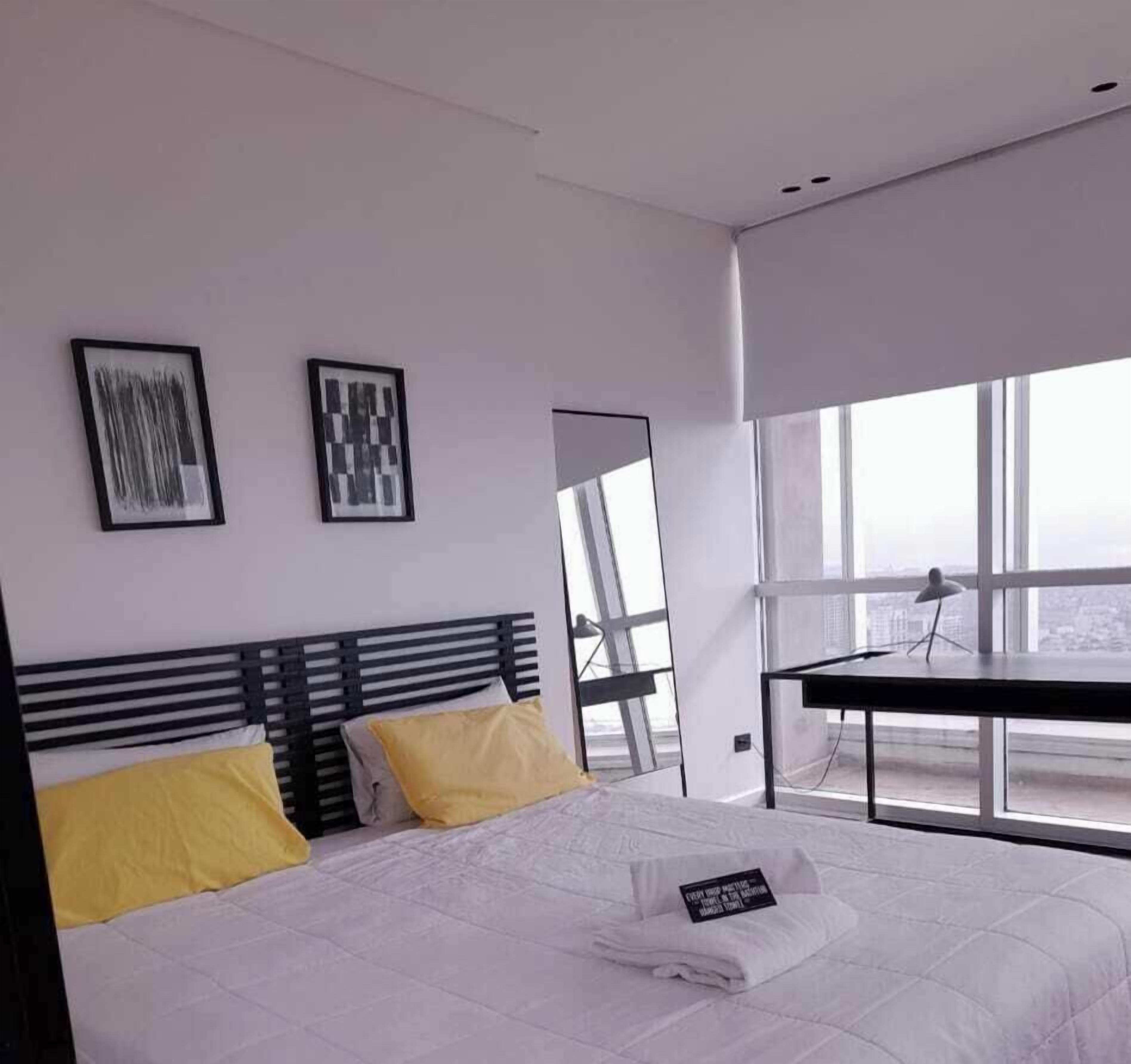 Une chambre d’hôtel moderne, dotée d’un grand lit, d’un bureau et offrant une vue sur la ville.
