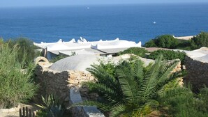 A coastal property with stone walls, white-roofed structures, and lush greenery. - Albergo I Dammusi Di Borgo Cala Creta (Lampedusa)