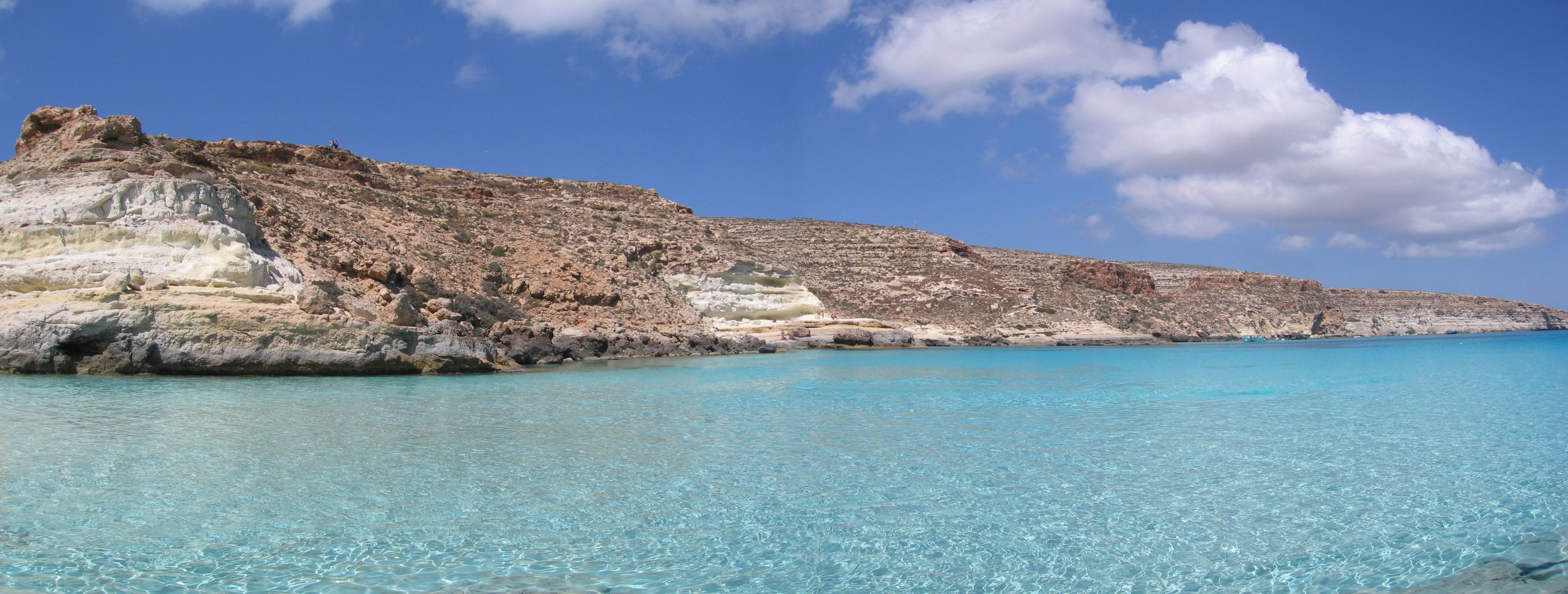 Eine Küstenlandschaft mit klarem türkisblauem Wasser und felsigen Klippen.