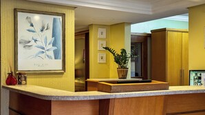 Una cocina con armarios de madera, encimera de mármol e impresión enmarcadas de motivos botánicos en la pared.
