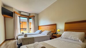 Habitación de hotel con dos camas, televisión, aire acondicionado y ventana con cortinas.