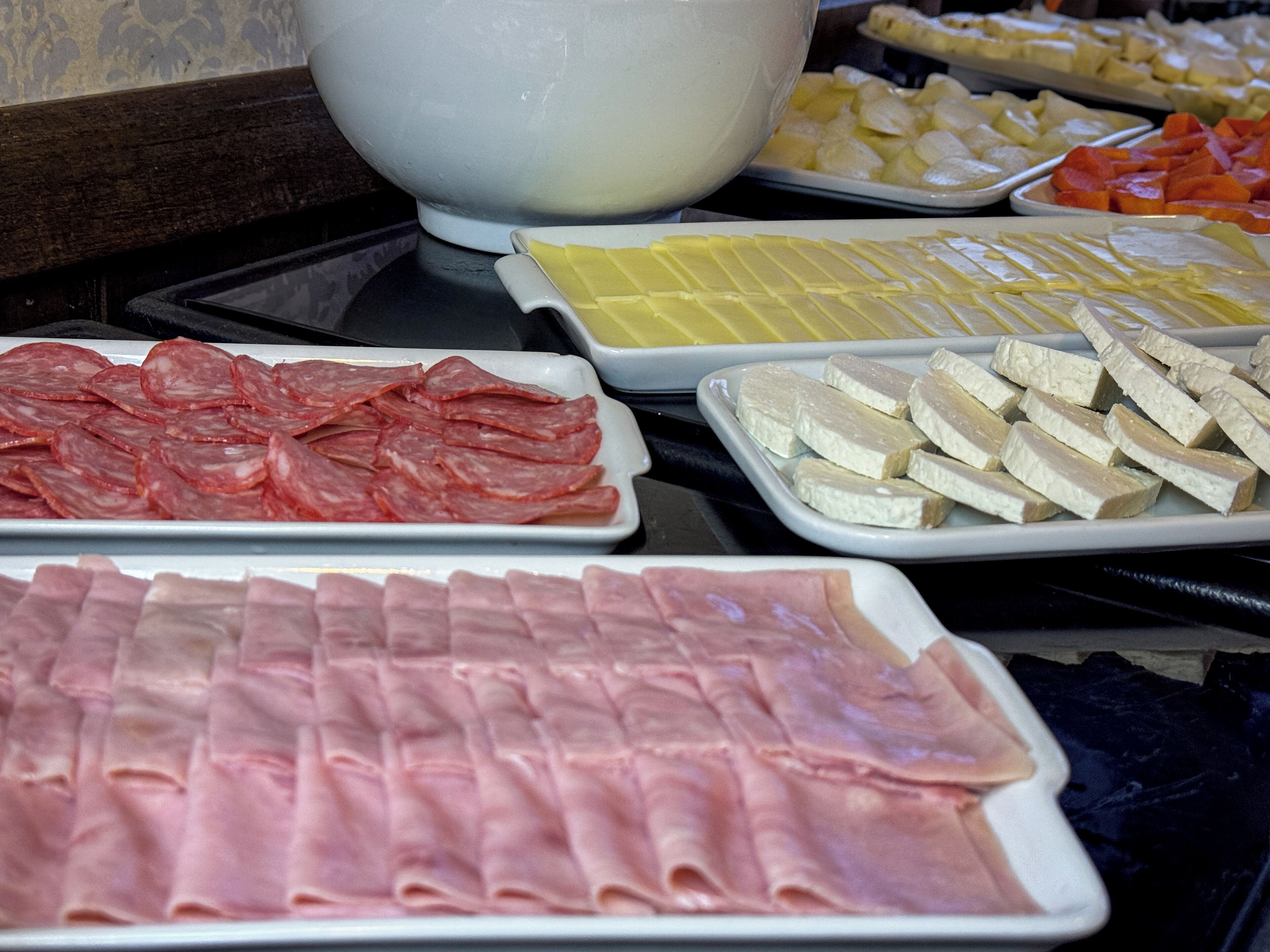A buffet with various food items including sliced meats and cheeses.