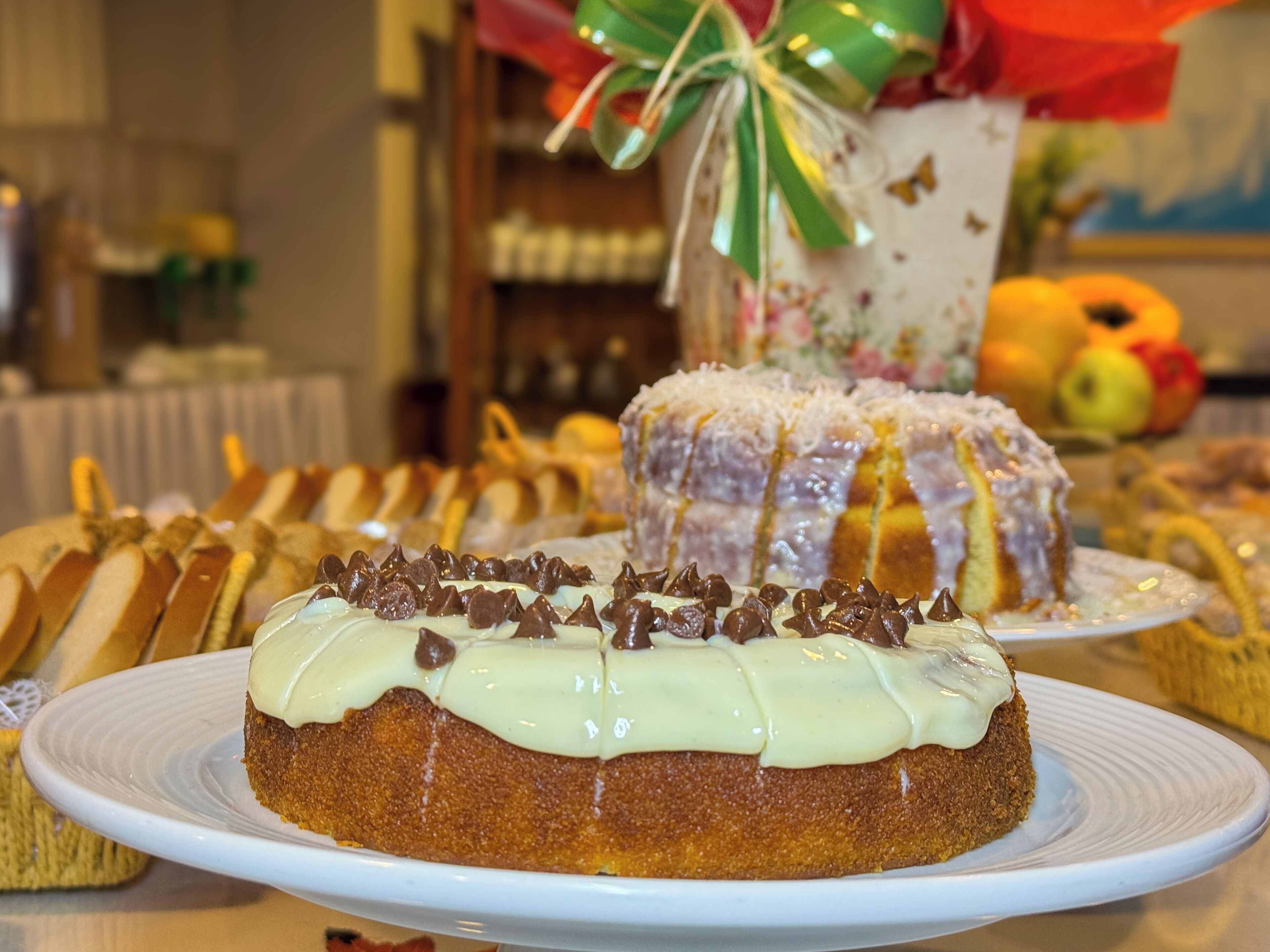 Variedad de postres sobre una mesa, incluyendo un pastel bundt con cobertura blanca y chispas de chocolate, y otras pastelerías.