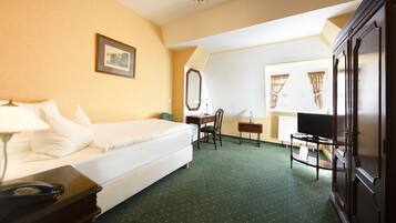 A hotel room with a bed, a desk, a chair, a television, and a wardrobe.