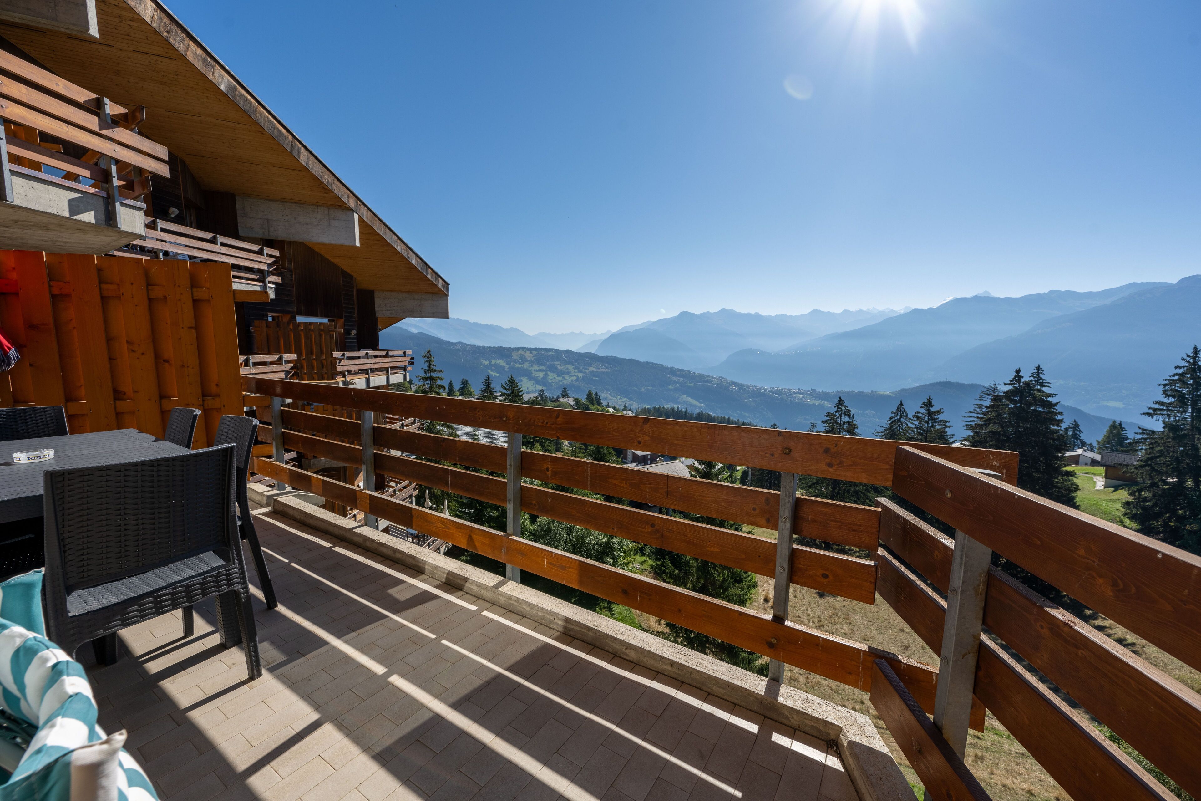 A balcony with a wooden railing overlooking a mountainous landscape.
