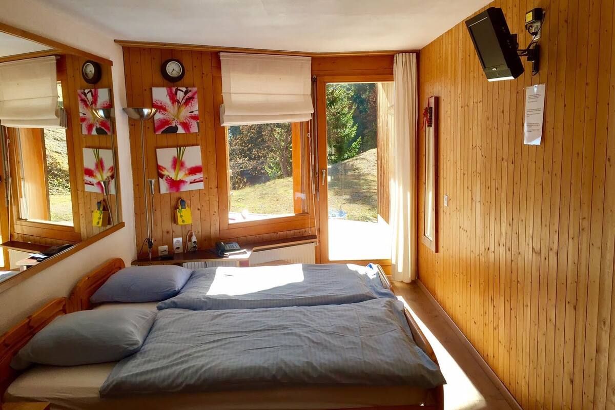 A room with a bed, a window with curtains, a clock, and a mirror.