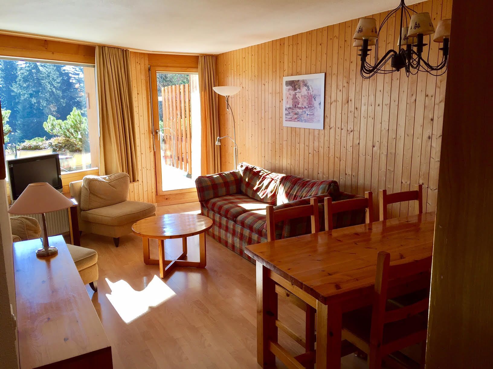 Una sala de estar acogedora con piso de madera, un sofá, una mesa de comedor y un televisor.