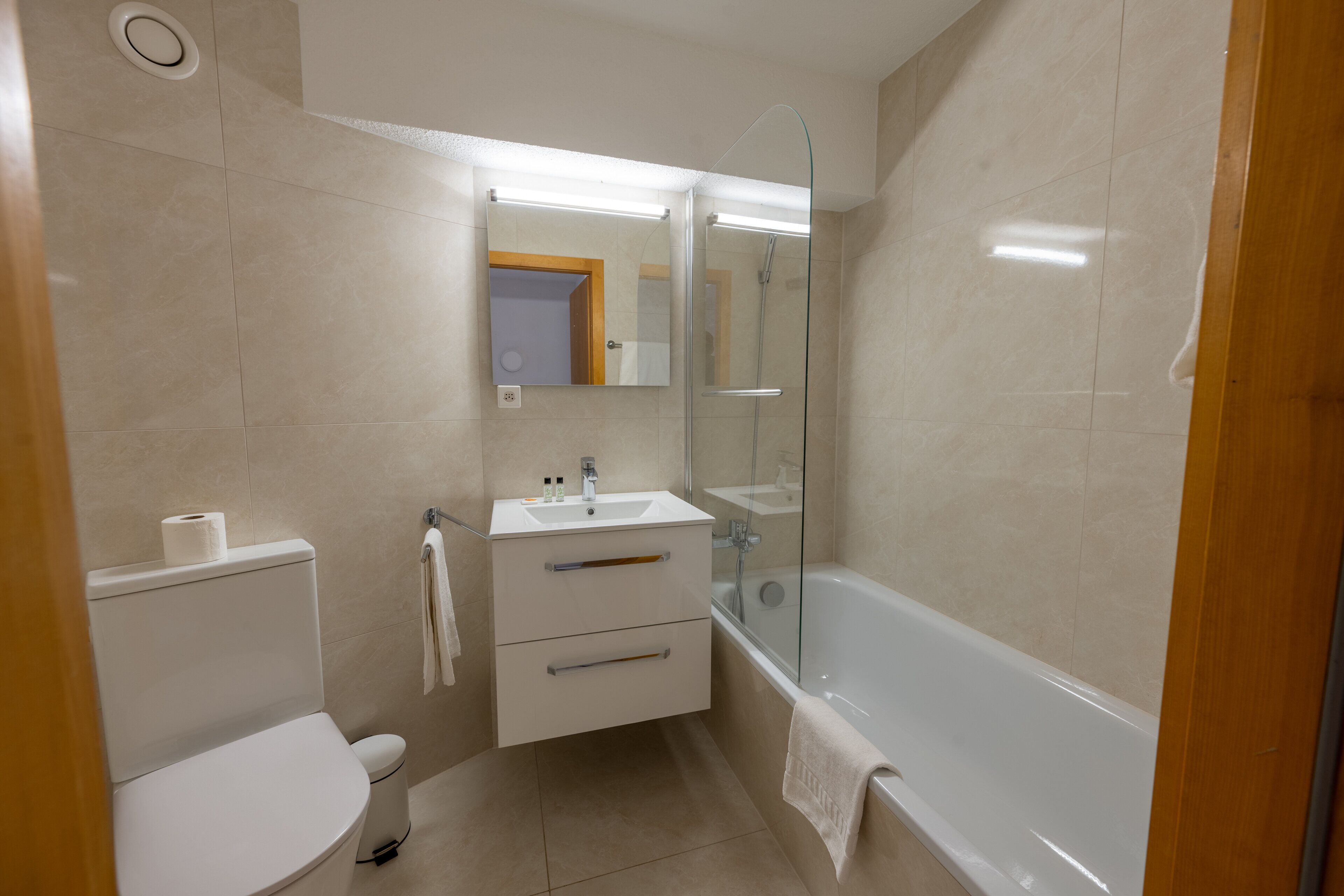 A modern bathroom with a toilet, sink, vanity, and bathtub.