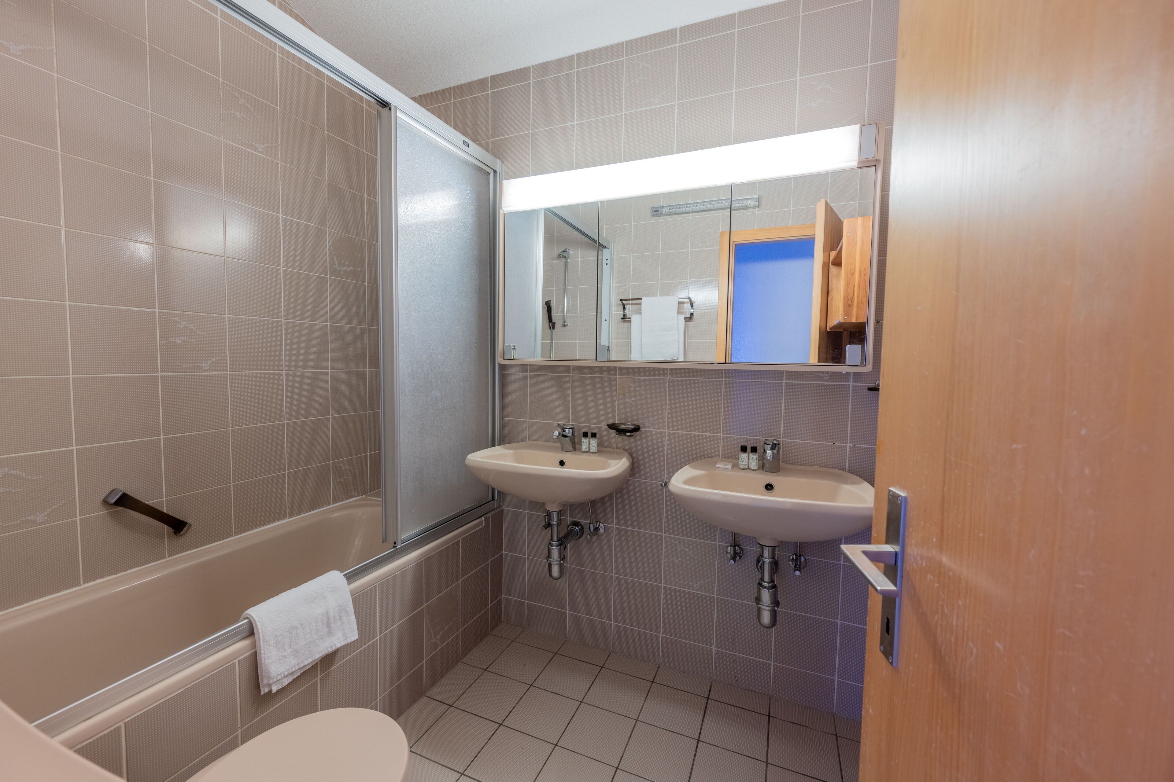 A modern bathroom with two sinks, a bathtub, and a shower.