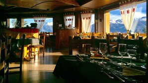 A restaurant with wooden interior and mountain views. - Eden Resort Anzère (Ayent)