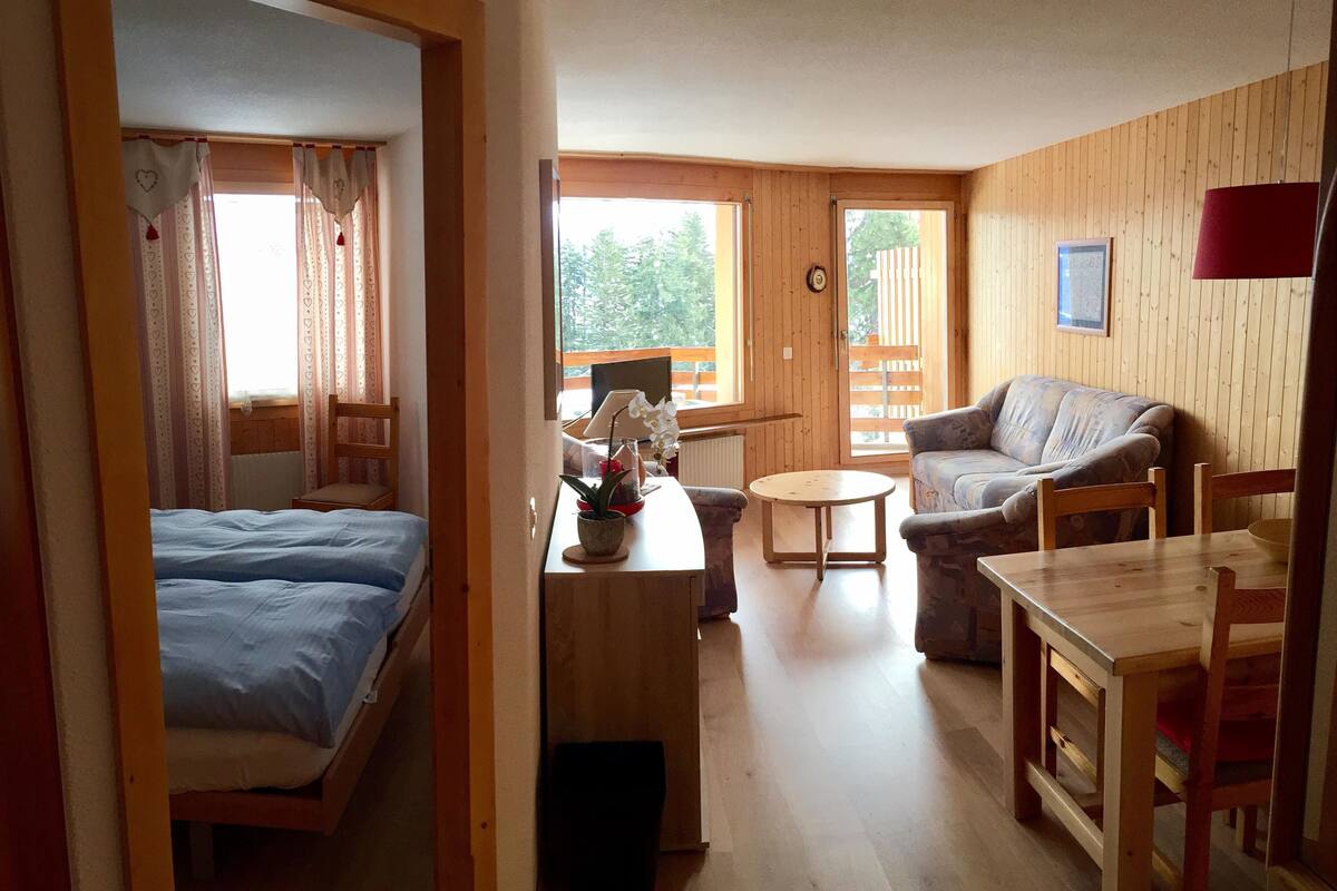 A cozy room with a bed, a sofa, a small table, and a chair.