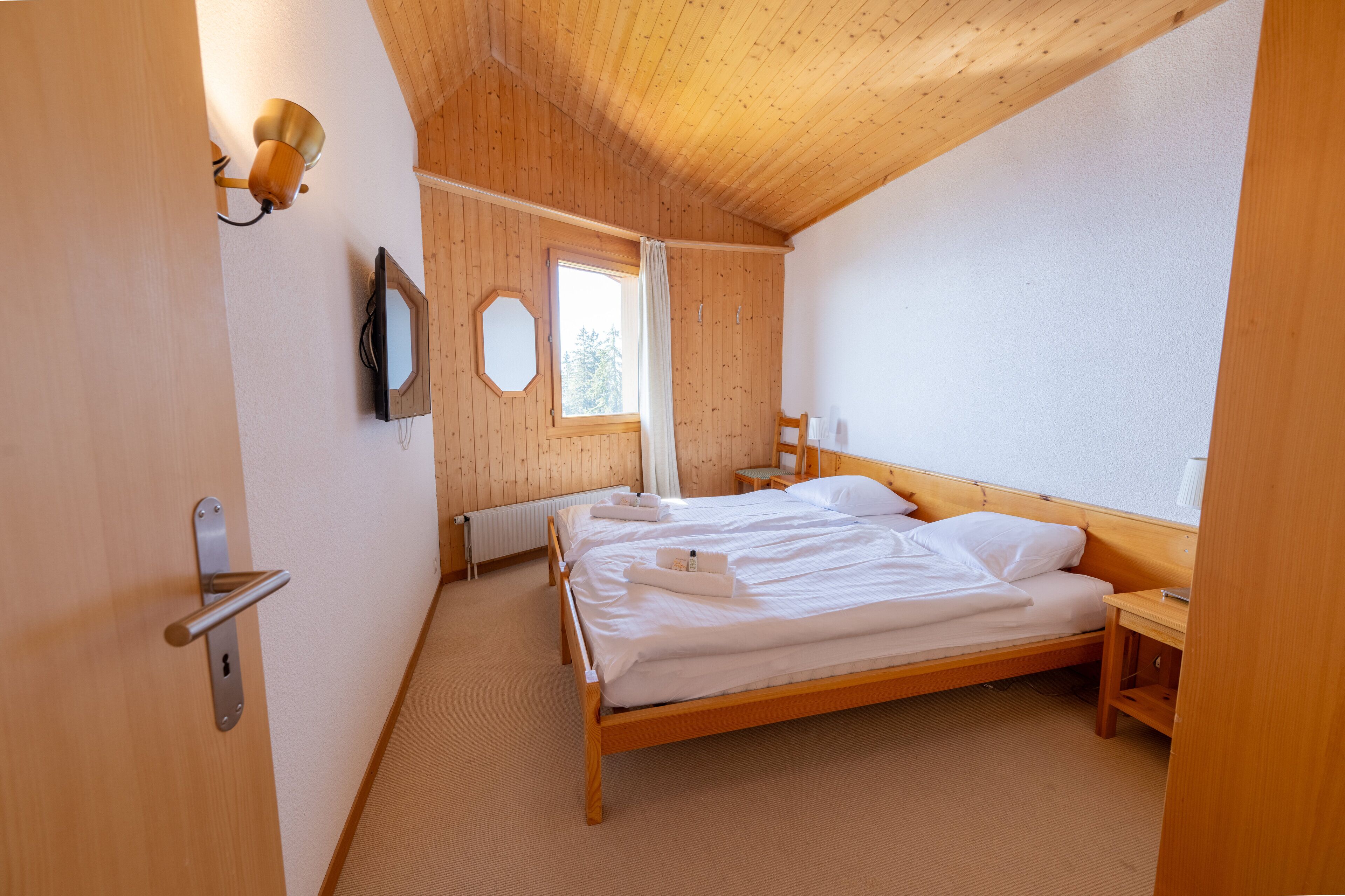 Un dormitorio con cama de madera, mesita de noche, espejo y ventana.