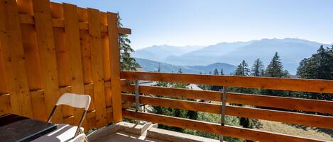Un balcon avec une balustrade en bois, une chaise blanche et une table.