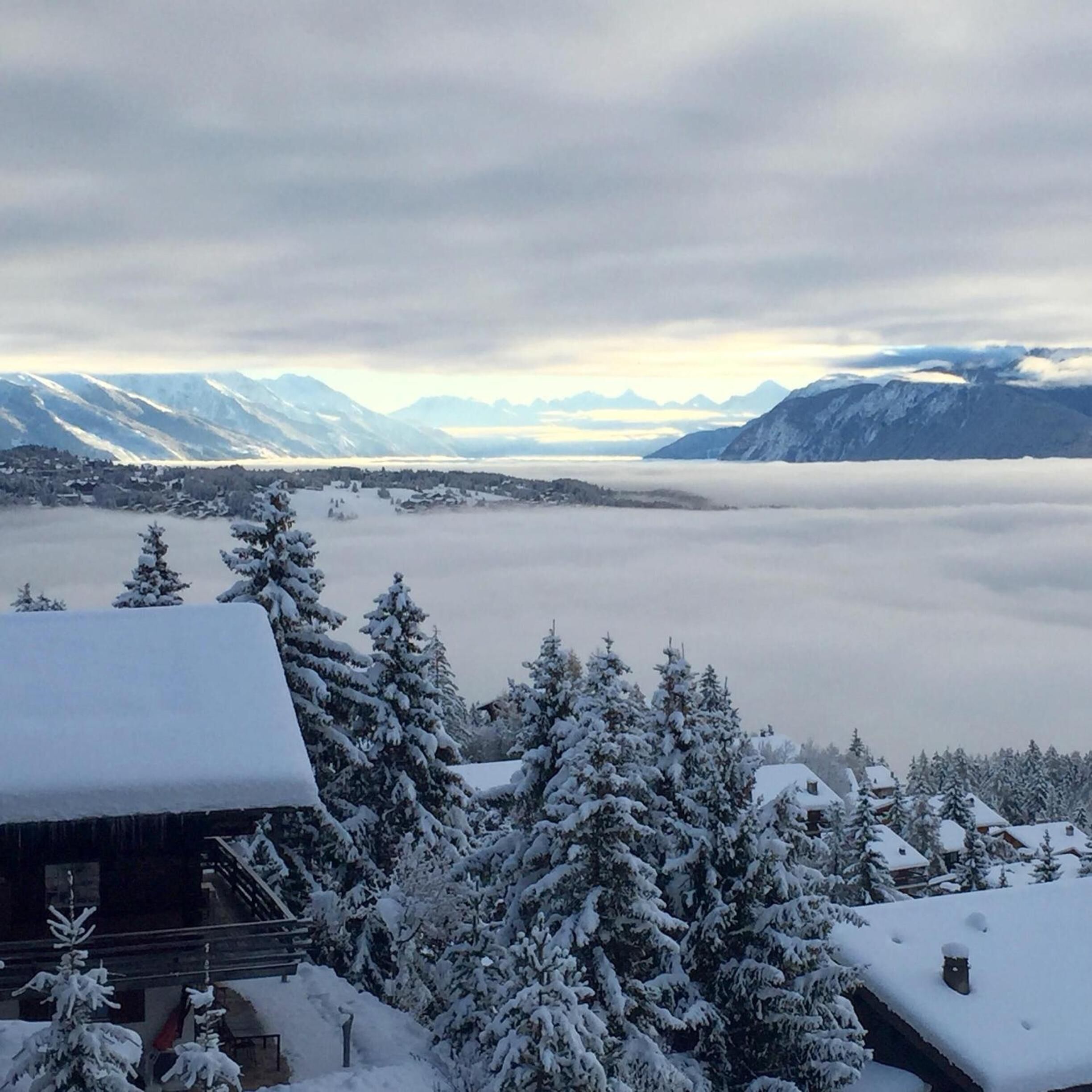 A mountain landscape with snow-covered trees and buildings, and a view of distant mountains.